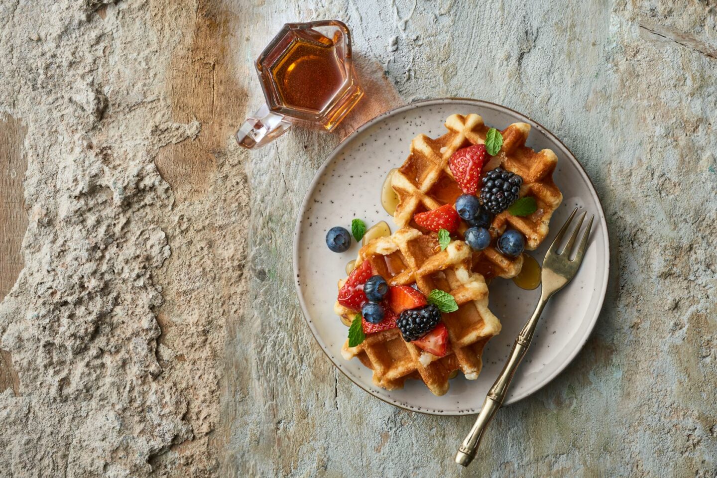 Waffles topped with fruit and maple syrup in a plate