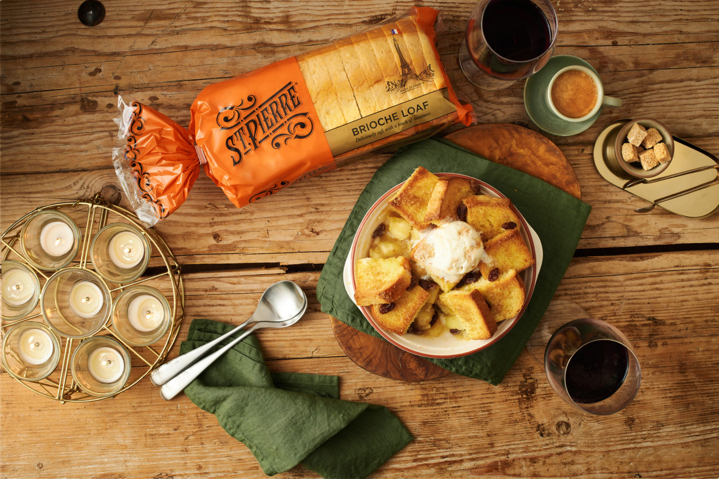 A table featuring a dessert made with brioche alongside candles and cutlery